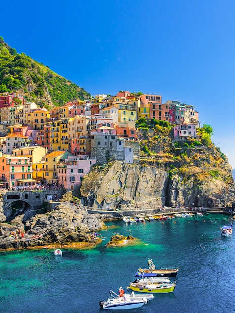 Colorful cliffside village of Manarola in Cinque Terre, Italy, with boats in the harbor.