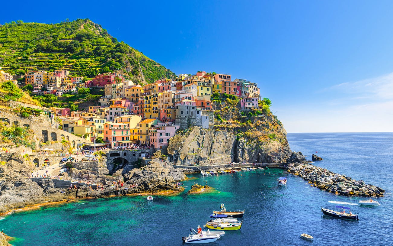 Colorful cliffside village of Manarola in Cinque Terre, Italy, with boats in the harbor.