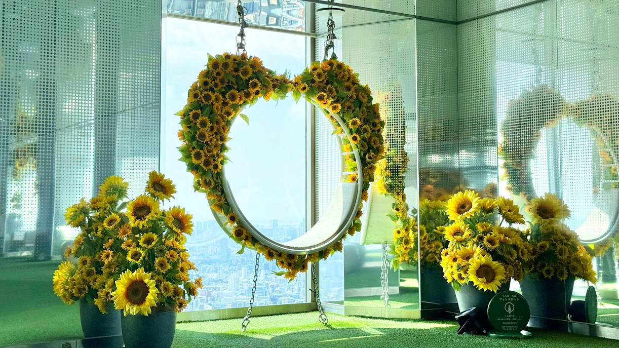 Sunflower-decorated swing at Sunshine 60 Observatory Tenbou Park with city view.