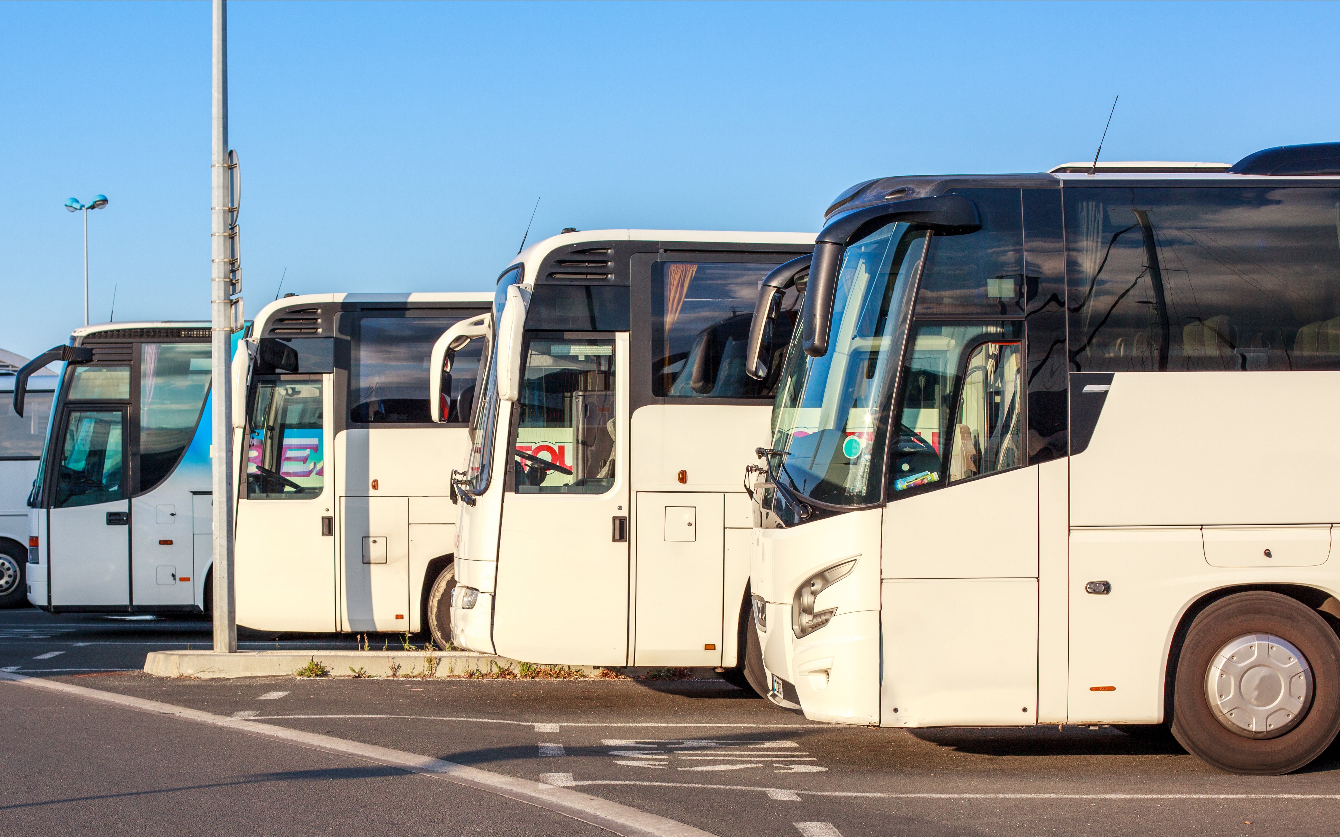 Buses parked at a station under a clear sky.