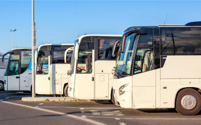 Buses parked at a station under a clear sky.