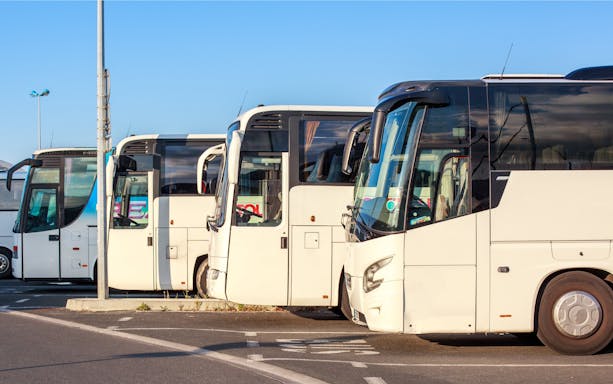 Buses parked at a station under a clear sky.