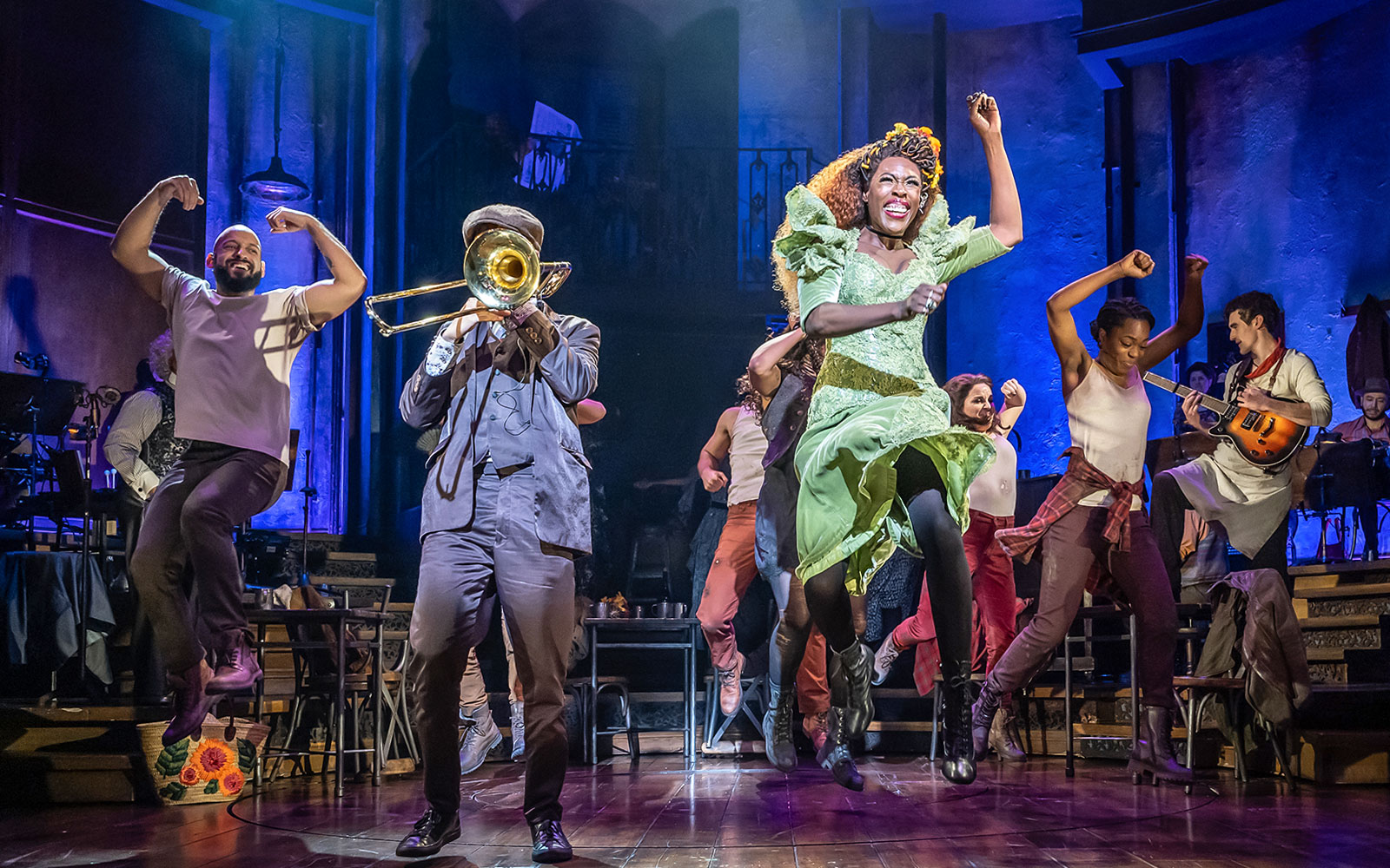 Performers dancing energetically on stage during Hadestown musical.