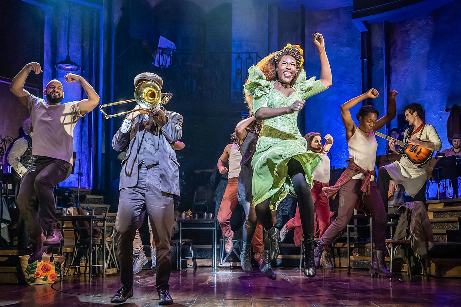 Performers dancing energetically on stage during Hadestown musical.