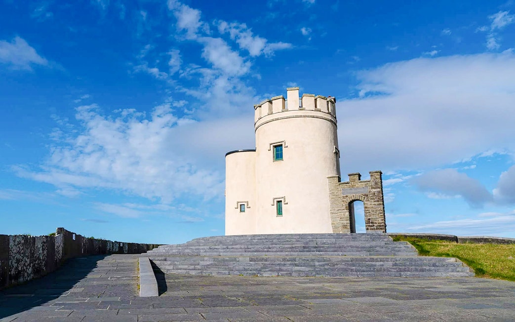 O'Brien's Tower at the Cliffs of Moher, Ireland, under a blue sky.