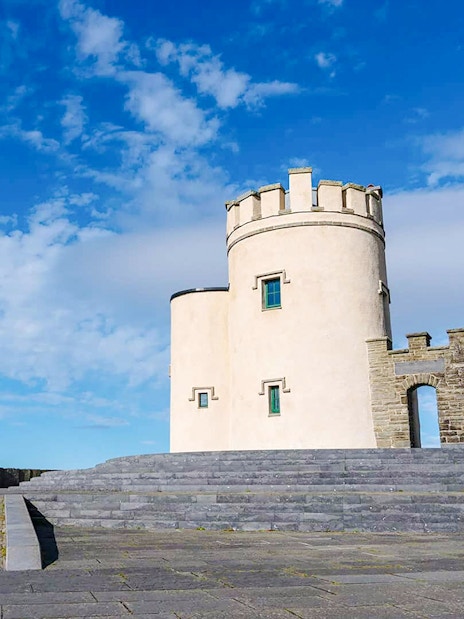 O'Brien's Tower at the Cliffs of Moher, Ireland, under a blue sky.