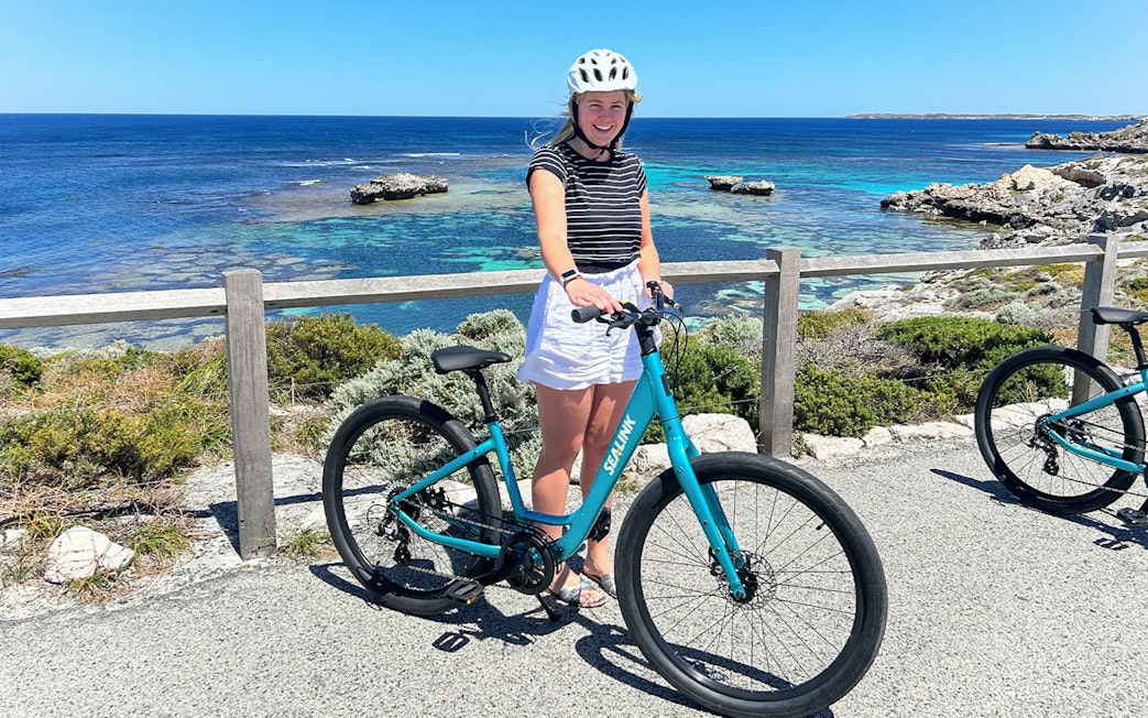 Person with a bike on Rottnest Island overlooking the ocean during a guided bus tour.