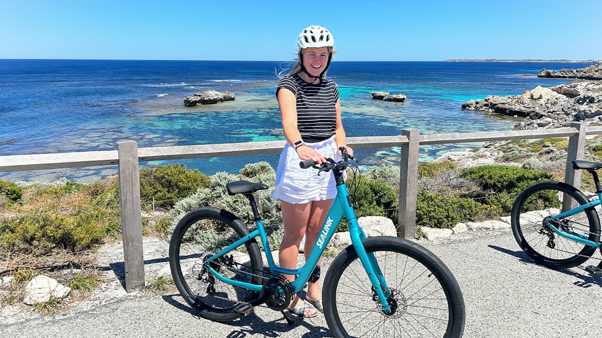 Person with a bike on Rottnest Island overlooking the ocean during a guided bus tour.