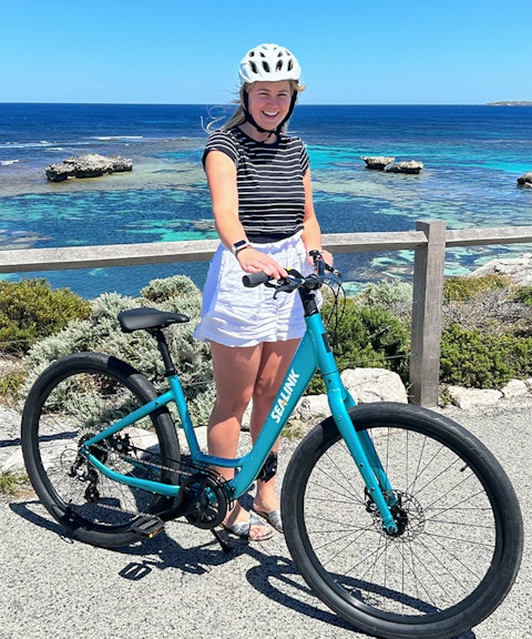 Person with a bike on Rottnest Island overlooking the ocean during a guided bus tour.
