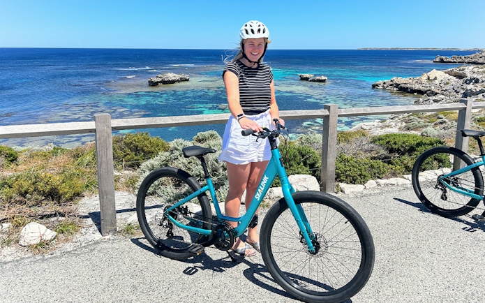 Person with a bike on Rottnest Island overlooking the ocean during a guided bus tour.