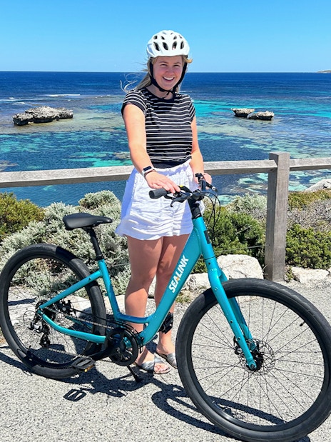 Person with a bike on Rottnest Island overlooking the ocean during a guided bus tour.