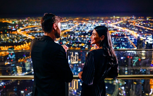Couple enjoying night view from Burj Khalifa Level 152 Lounge, Dubai.