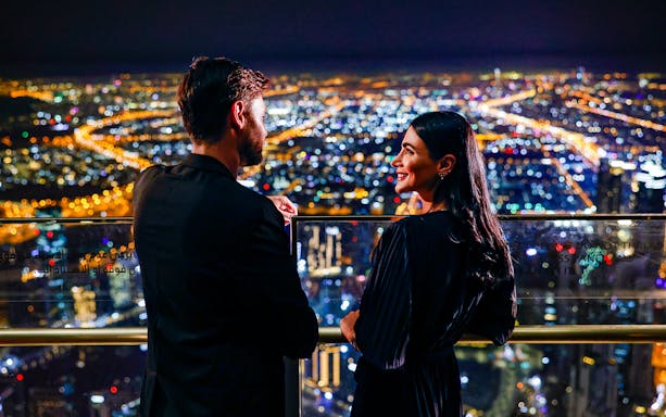 Couple enjoying night view from Burj Khalifa Level 152 Lounge, Dubai.