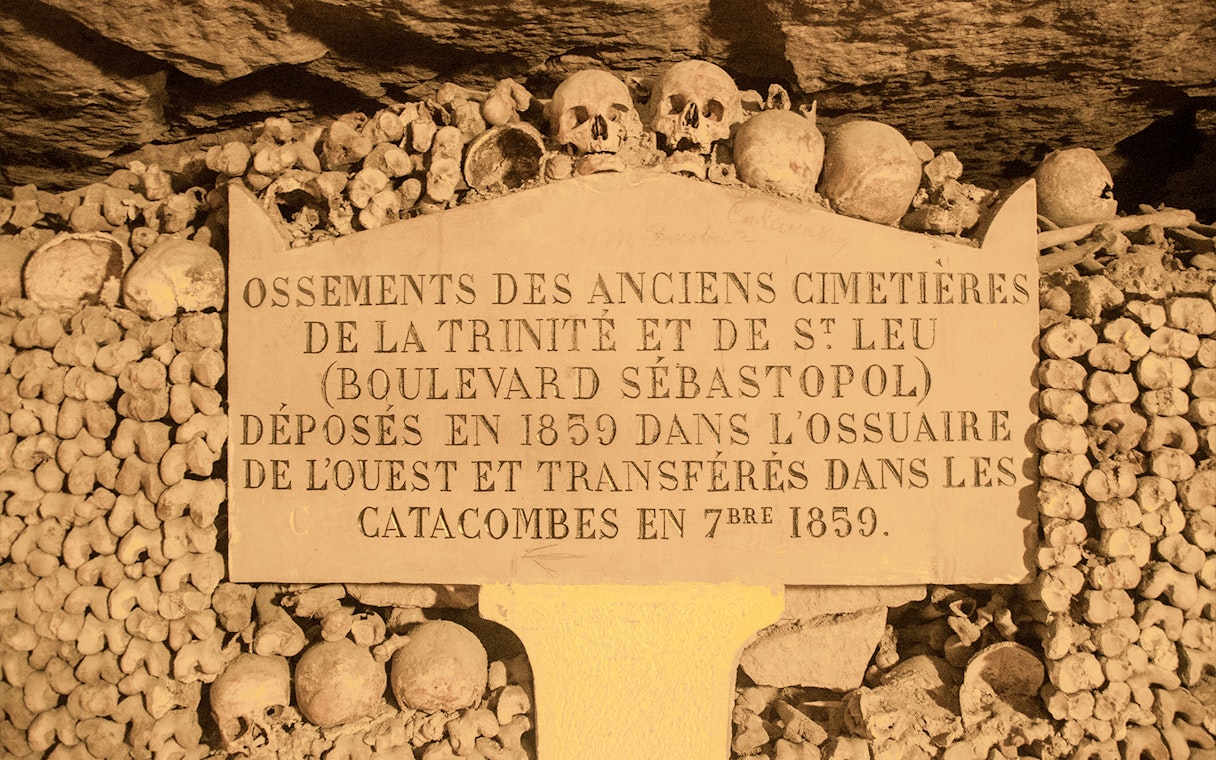 Information board in Paris Catacombs with skulls and bones, part of Small Group Guided Tour.