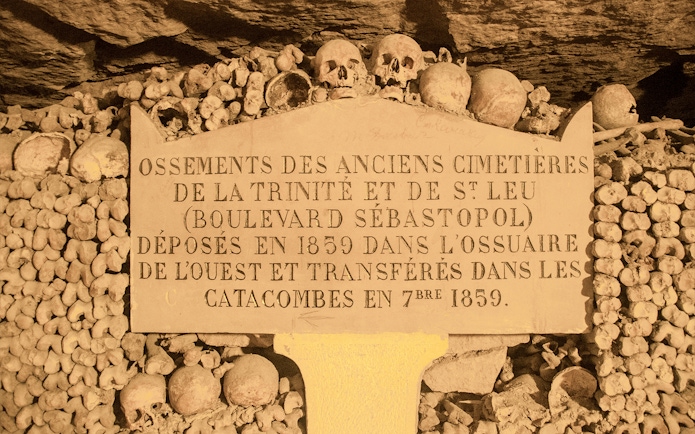 Information board in Paris Catacombs with skulls and bones, part of Small Group Guided Tour.