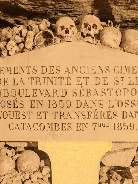 Information board in Paris Catacombs with skulls and bones, part of Small Group Guided Tour.