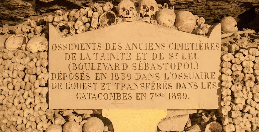 Information board in Paris Catacombs with skulls and bones, part of Small Group Guided Tour.