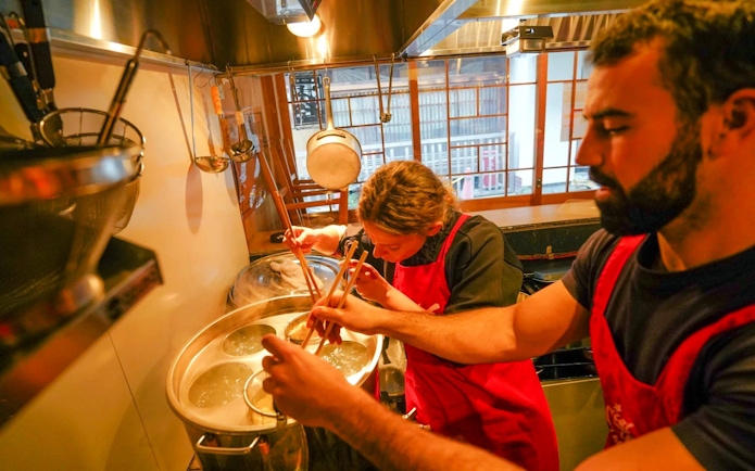 Participants cooking ramen in a Kyoto kitchen during a ramen and gyoza class.