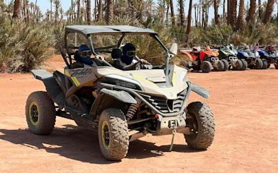 Buggy ride through palm oasis in Marrakech with parked ATVs in background.