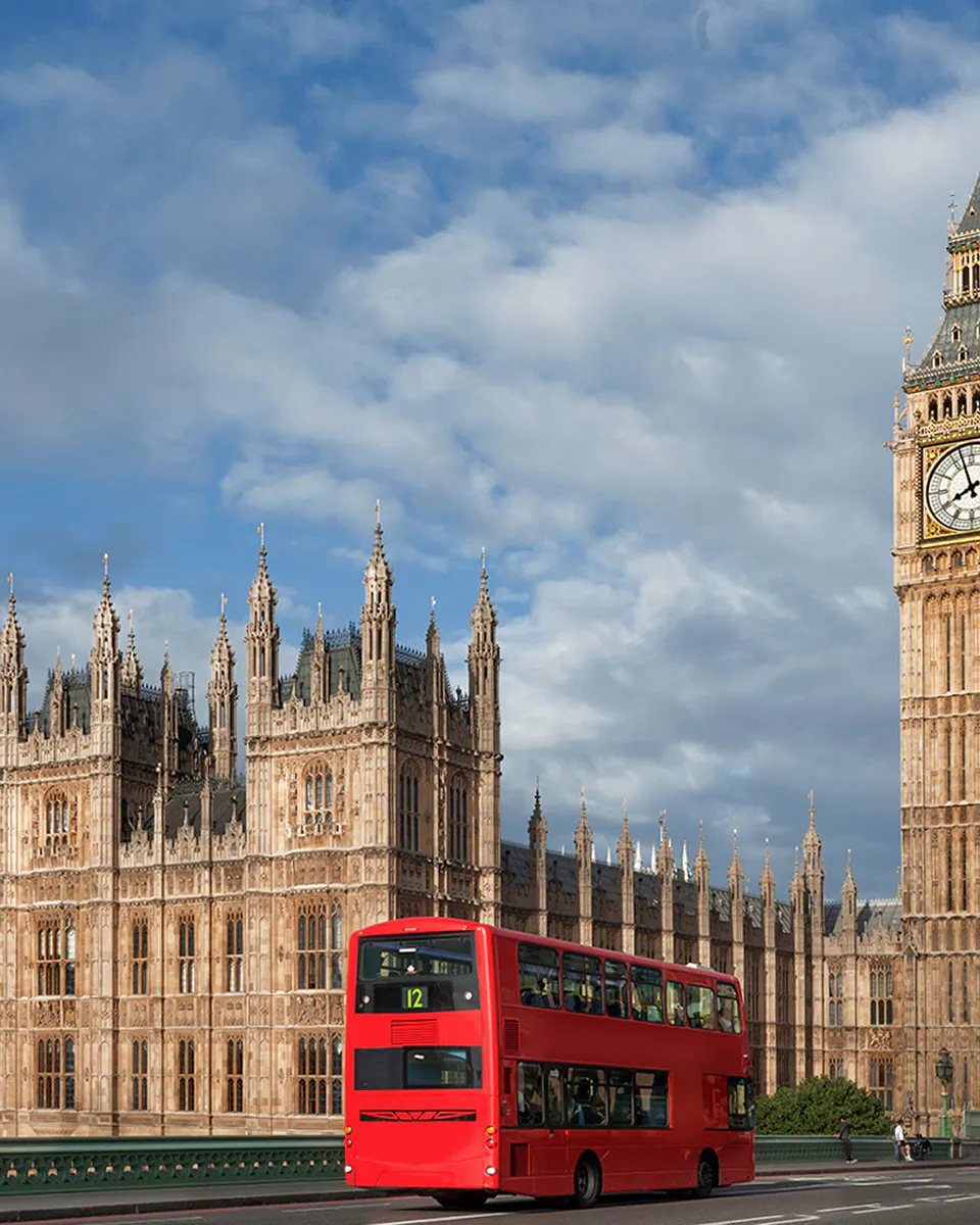 Big Ben and Palace of Westminster with red double-decker bus in London.
