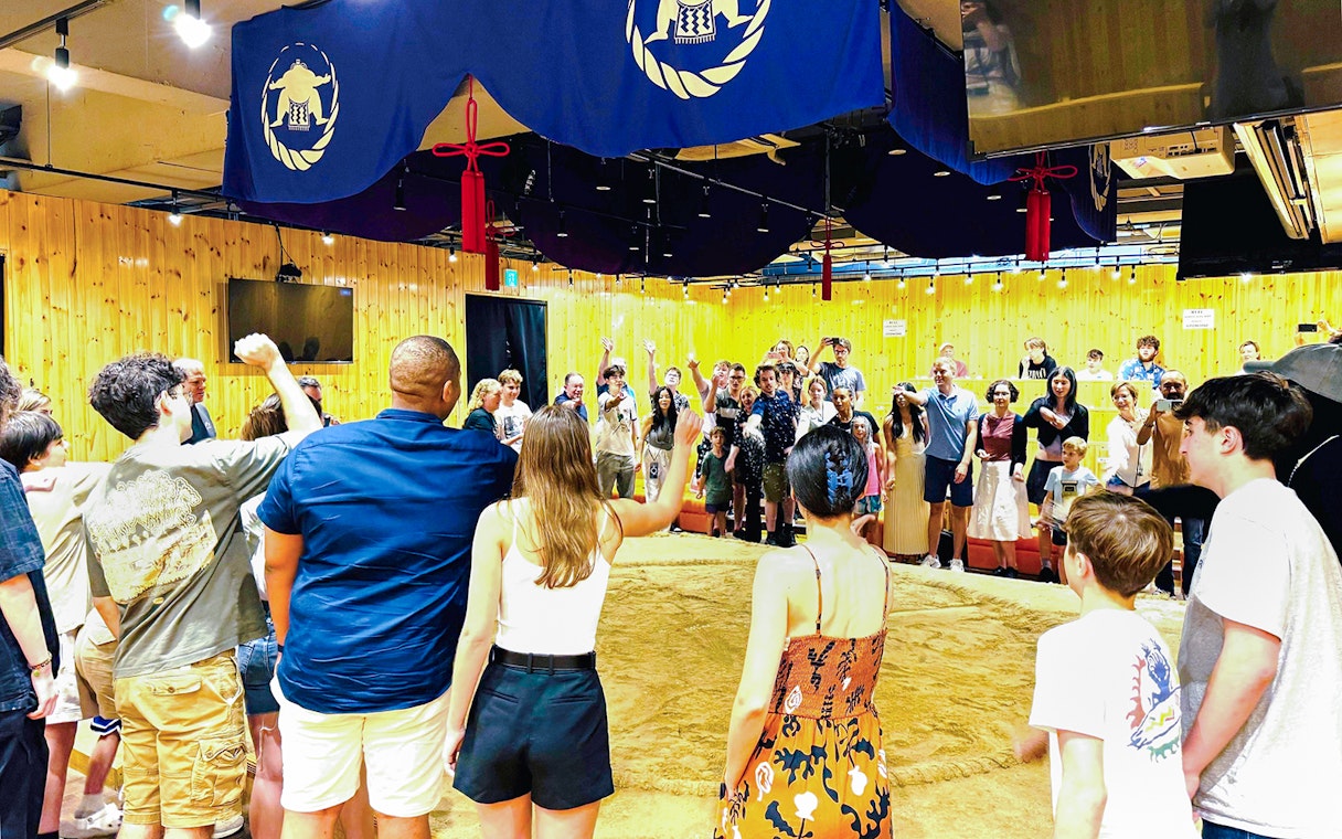 Sumo show audience in Tokyo enjoying the experience with a group photo opportunity.