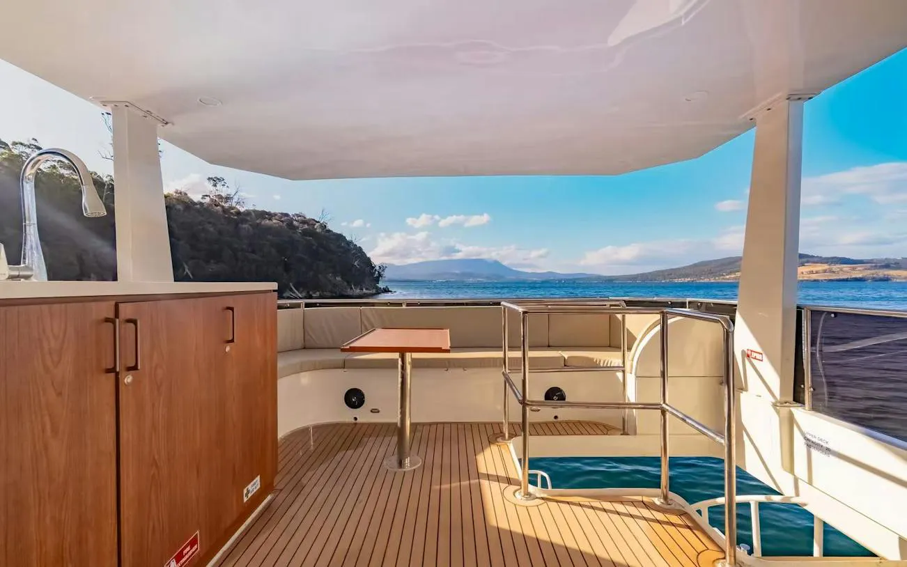 Cruise deck with seating and ocean view on Hobart Half-Day Fishing, Diving & Gourmet Cruise.
