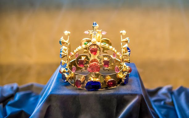 Golden crown with colorful gemstones displayed at Prague Castle.