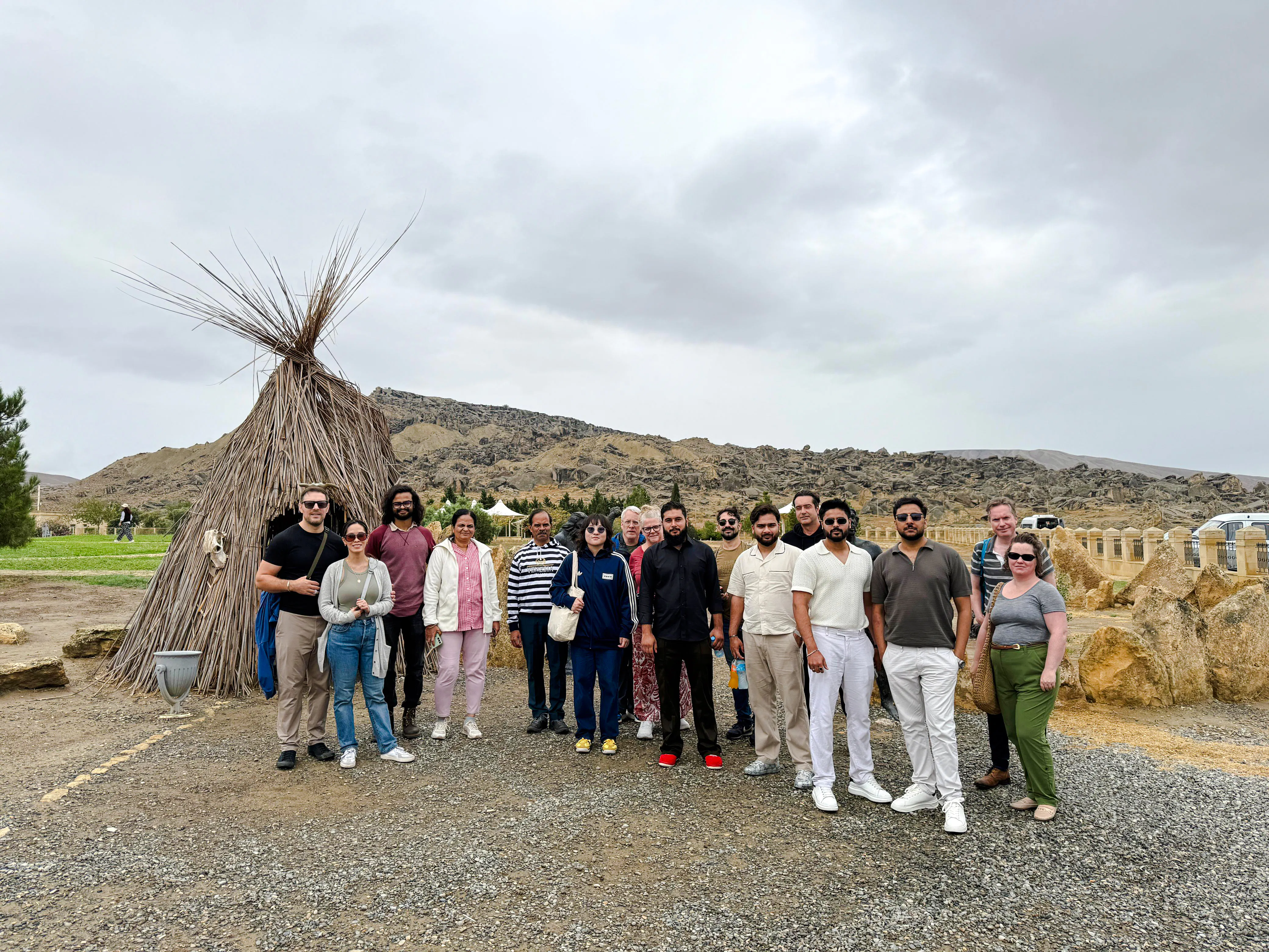 Group of tourists at Gobustan National Park with traditional hut and rocky landscape, Baku.