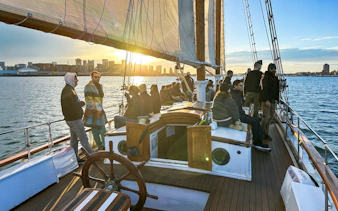 People enjoying a sunset cruise on the Liberty Star with city skyline in the background.