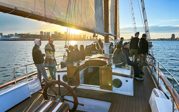 People enjoying a sunset cruise on the Liberty Star with city skyline in the background.