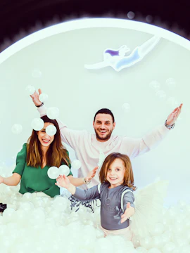 Family enjoying interactive exhibit at Selfie Museum with white balls.