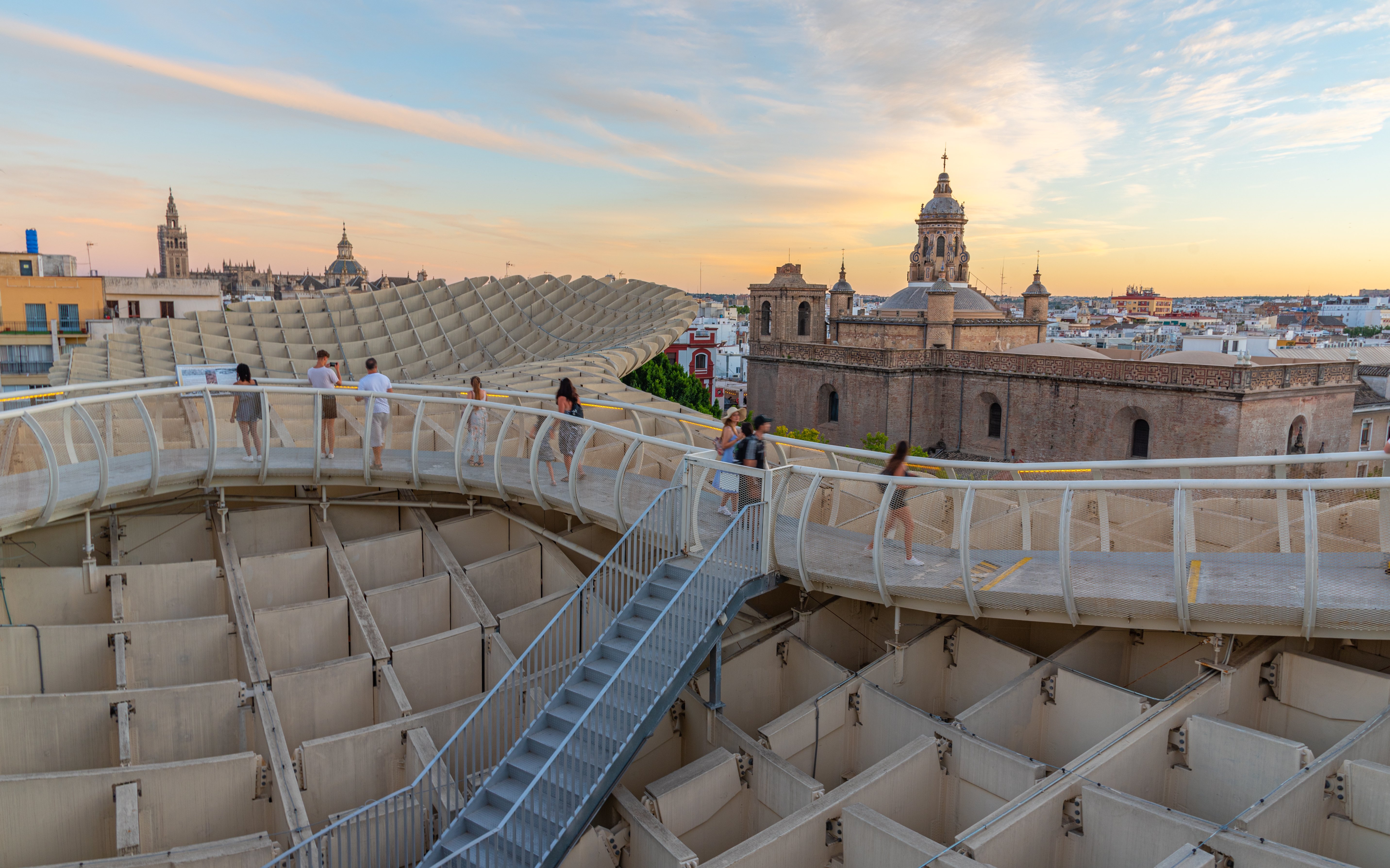 Visitors walking on Setas de Sevilla walkway at sunset, Seville, Spain.