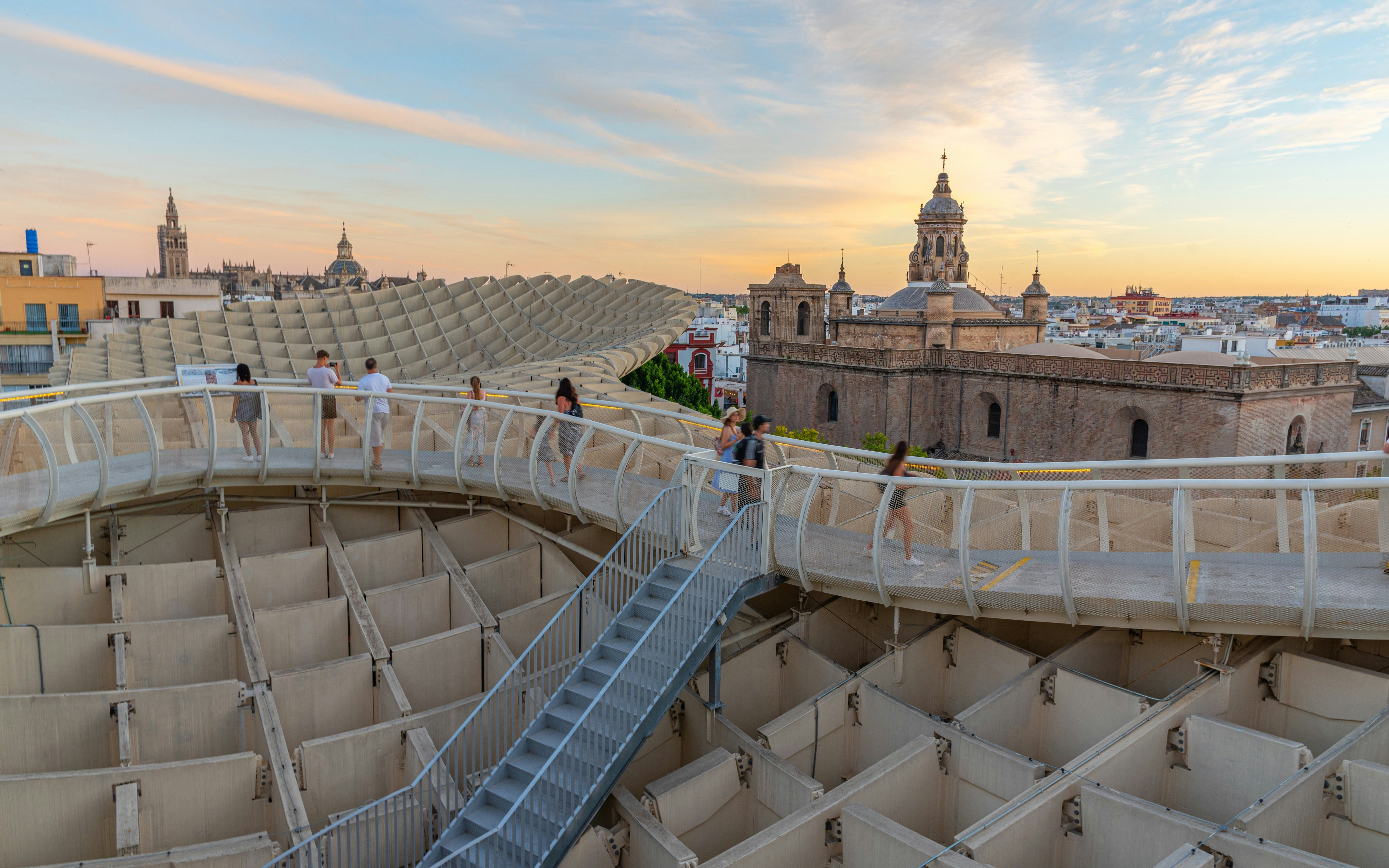 Visitors walking on Setas de Sevilla walkway at sunset, Seville, Spain.
