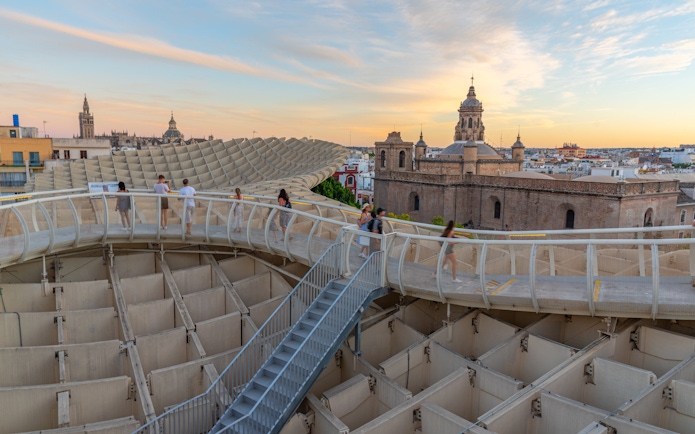 Visitors walking on Setas de Sevilla walkway at sunset, Seville, Spain.
