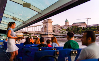 Guests enjoying Budapest Sunset Cruise with view of Chain Bridge and Buda Castle.