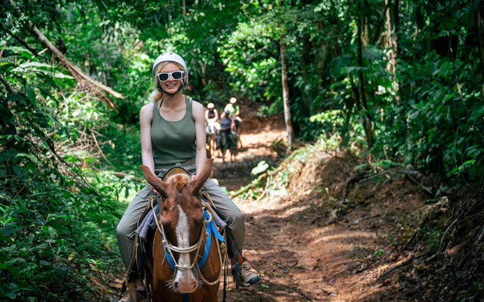 Horseback riding through lush jungle trail in Manuel Antonio.