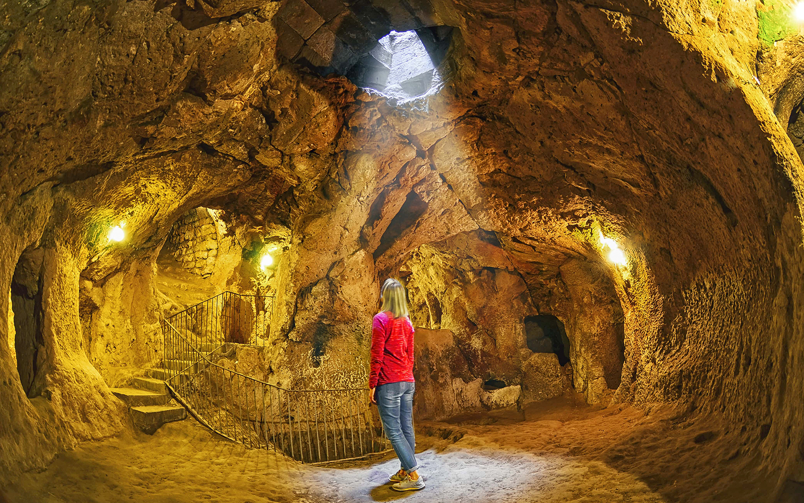 Visitor exploring an underground cave in Cappadocia during a guided tour.