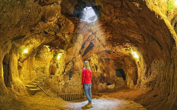 Visitor exploring an underground cave in Cappadocia during a guided tour.