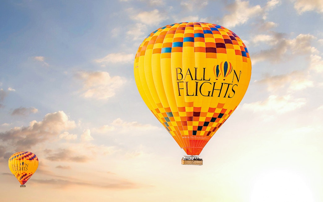 Hot air balloon in the sky during sunrise, part of a tour with hotel transfers, breakfast, camel ride, and quad biking.