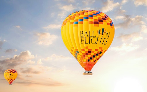 Hot air balloon in the sky during sunrise, part of a tour with hotel transfers, breakfast, camel ride, and quad biking.