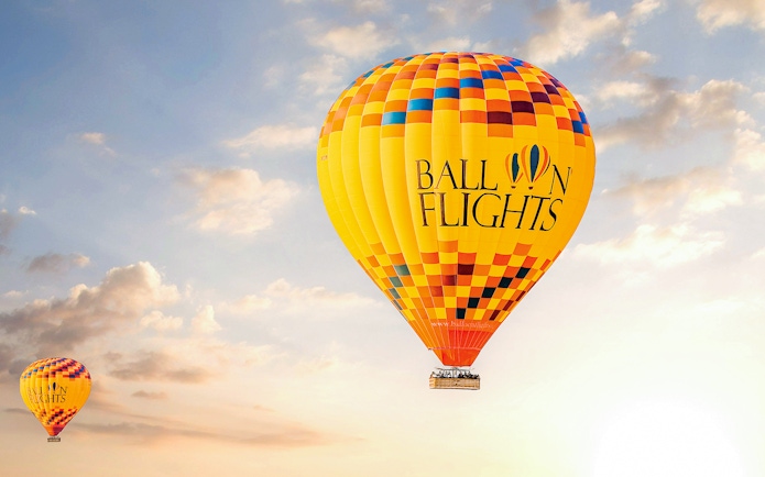 Hot air balloon in the sky during sunrise, part of a tour with hotel transfers, breakfast, camel ride, and quad biking.