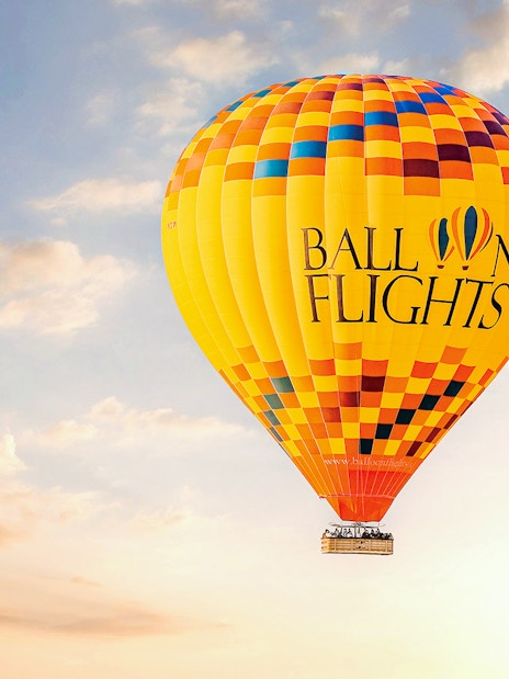 Hot air balloon in the sky during sunrise, part of a tour with hotel transfers, breakfast, camel ride, and quad biking.