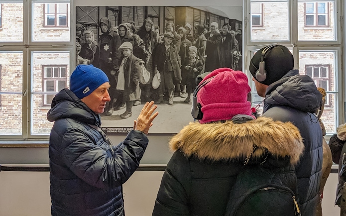 Guide explaining historical photo during Auschwitz Birkenau tour from Wroclaw.