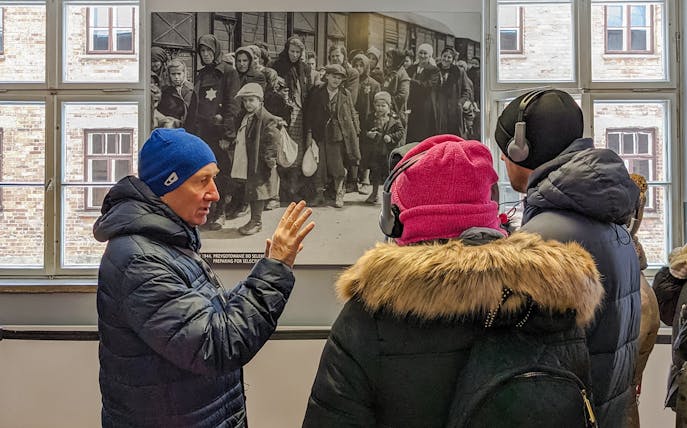 Guide explaining historical photo during Auschwitz Birkenau tour from Wroclaw.