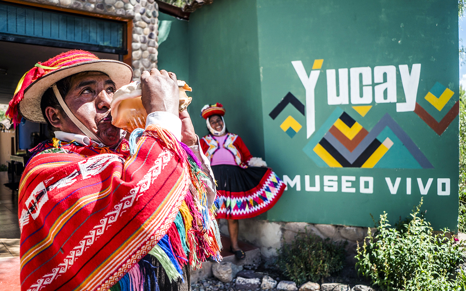 Peruvian man in traditional attire playing a conch shell at Yucay Museo Vivo, Sacred Valley, Peru.