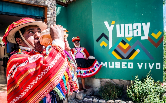 Peruvian man in traditional attire playing a conch shell at Yucay Museo Vivo, Sacred Valley, Peru.