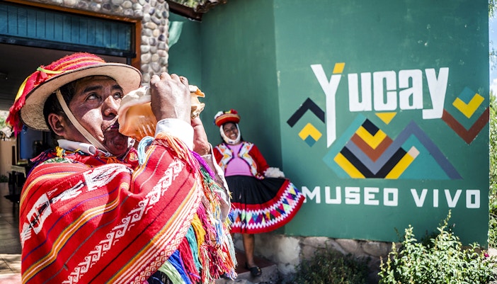 Peruvian man in traditional attire playing a conch shell at Yucay Museo Vivo, Sacred Valley, Peru.