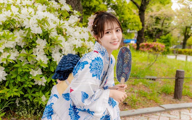 Tourist in Yukata posing among vibrant flowers in Japan.
