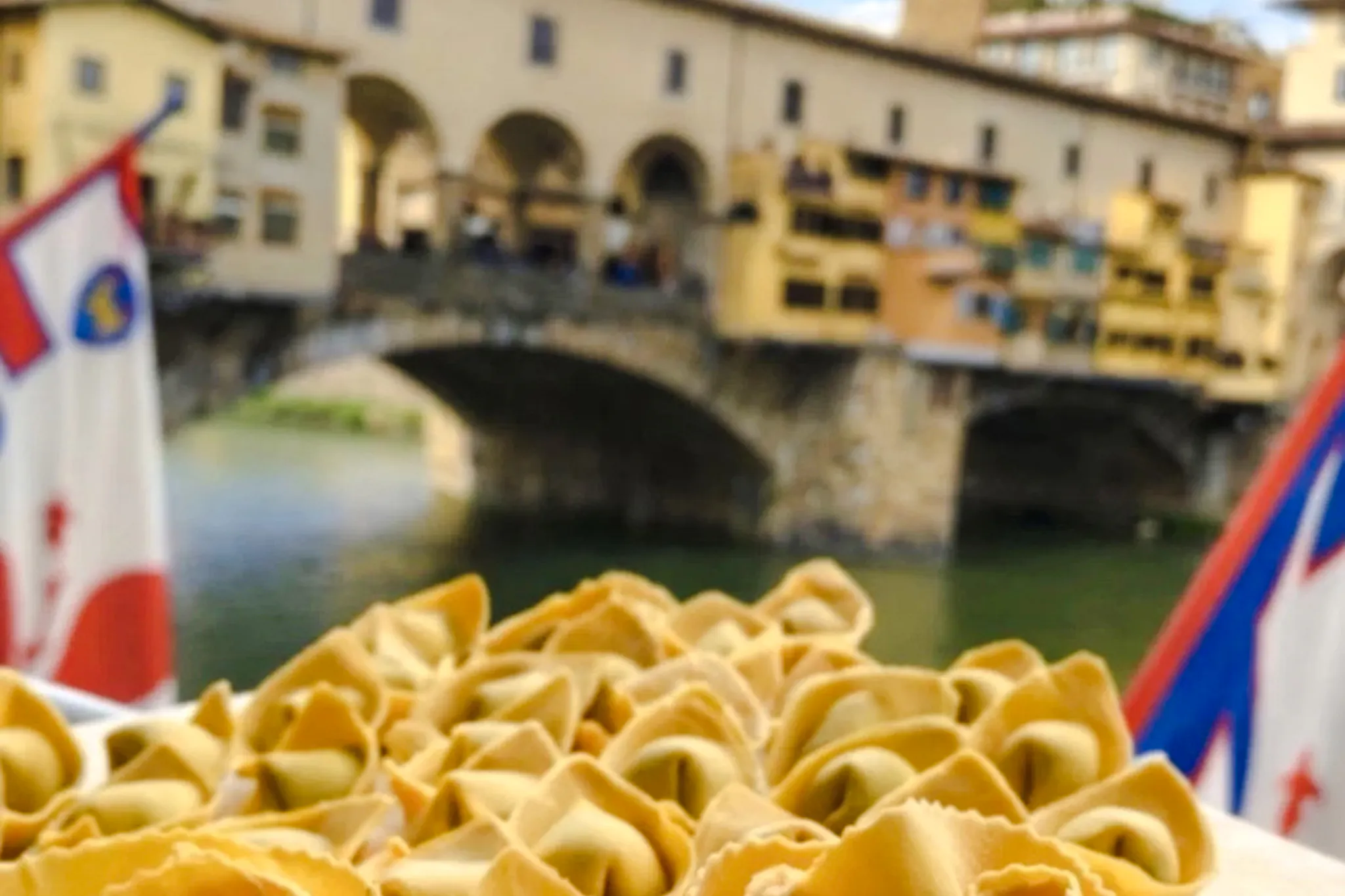 Pasta dish with Ponte Vecchio in the background during a Florence small-group cooking class.