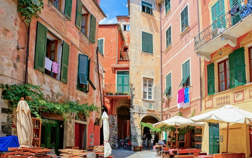 Colorful buildings and outdoor cafes in a narrow street of Cinque Terre, Italy.